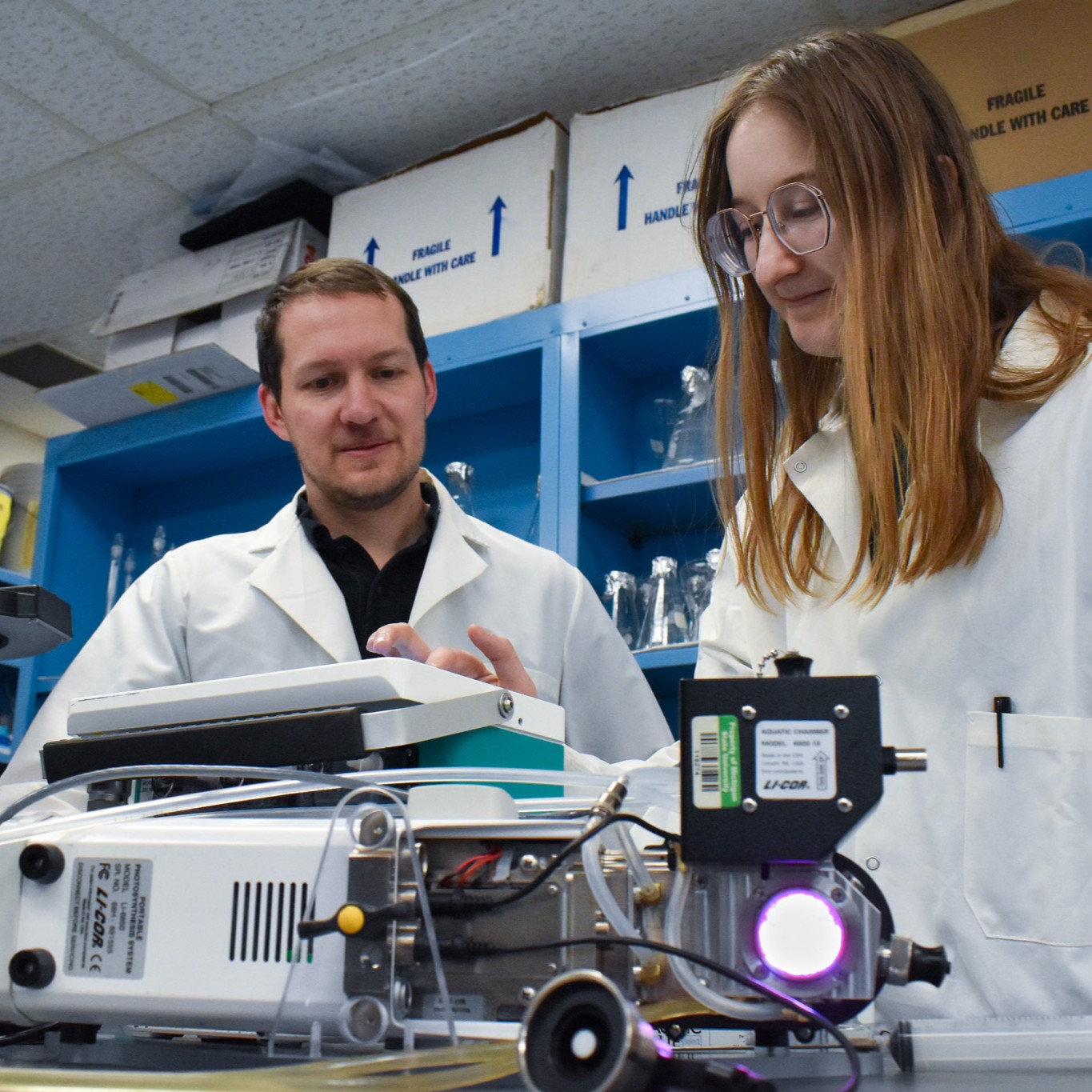 Two people in a lab use scientific equipment