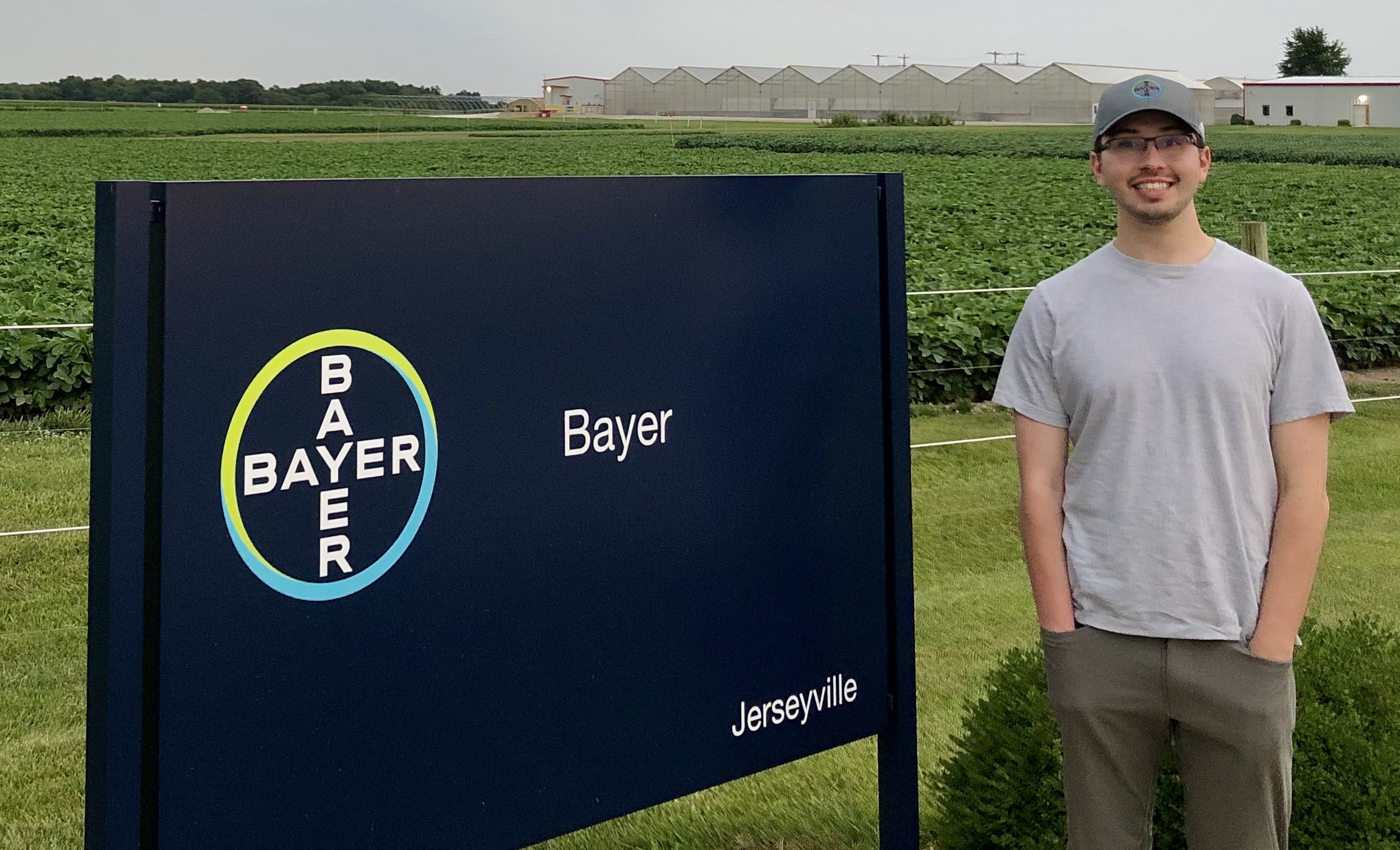 Man stands outside with sign that reads Bayer