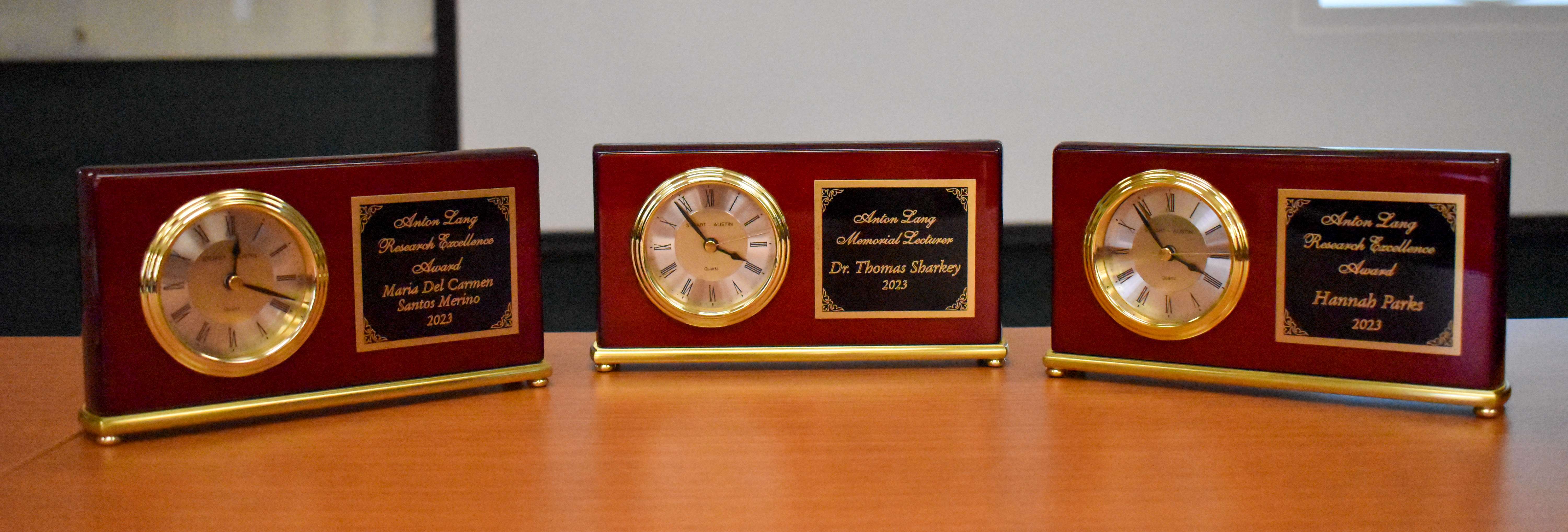 Three award clocks with plaques 