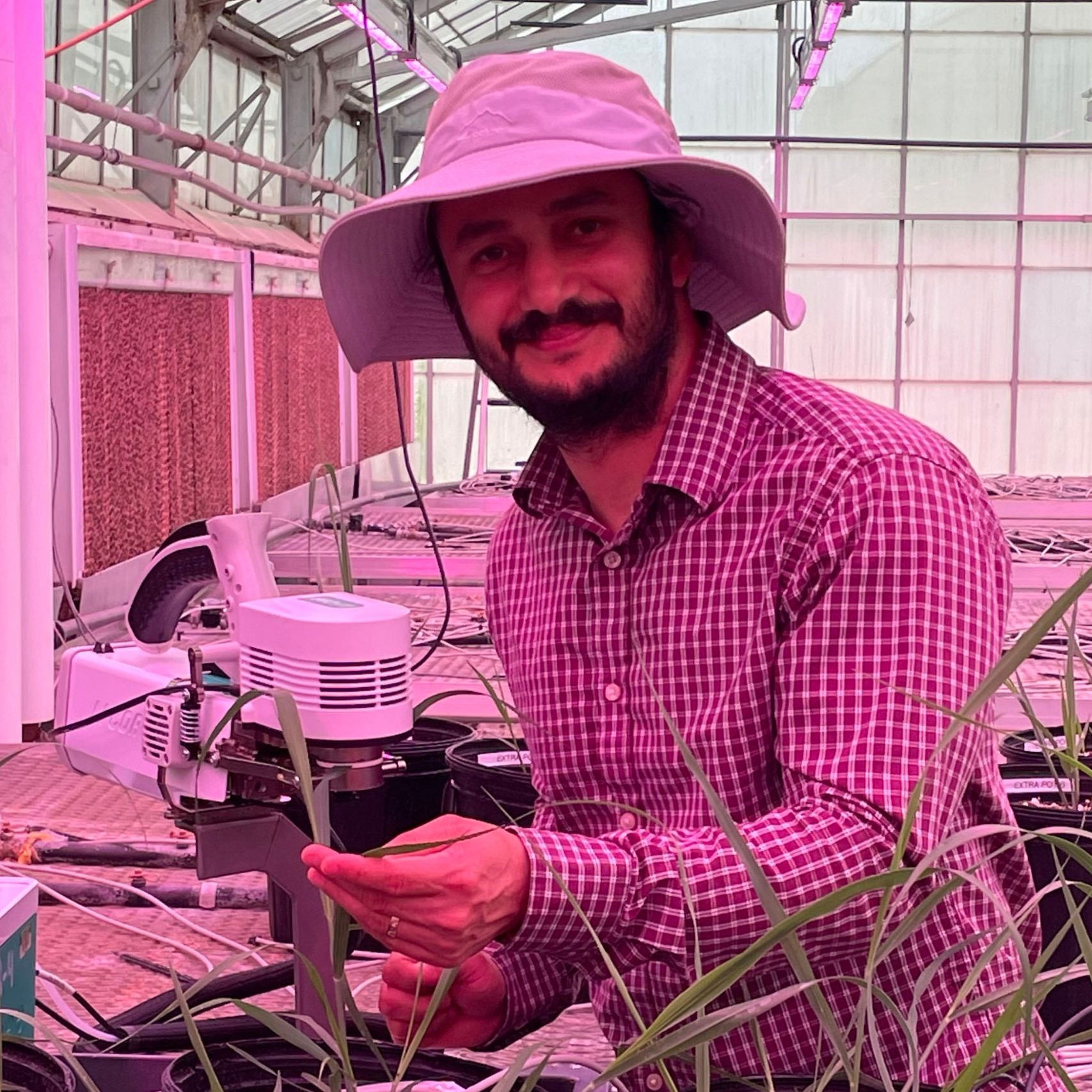 Binod Basyal in a greenhouse, working with a piece of scientific equipment