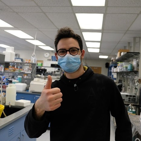 A person in a lab gives a thumbs up to the camera