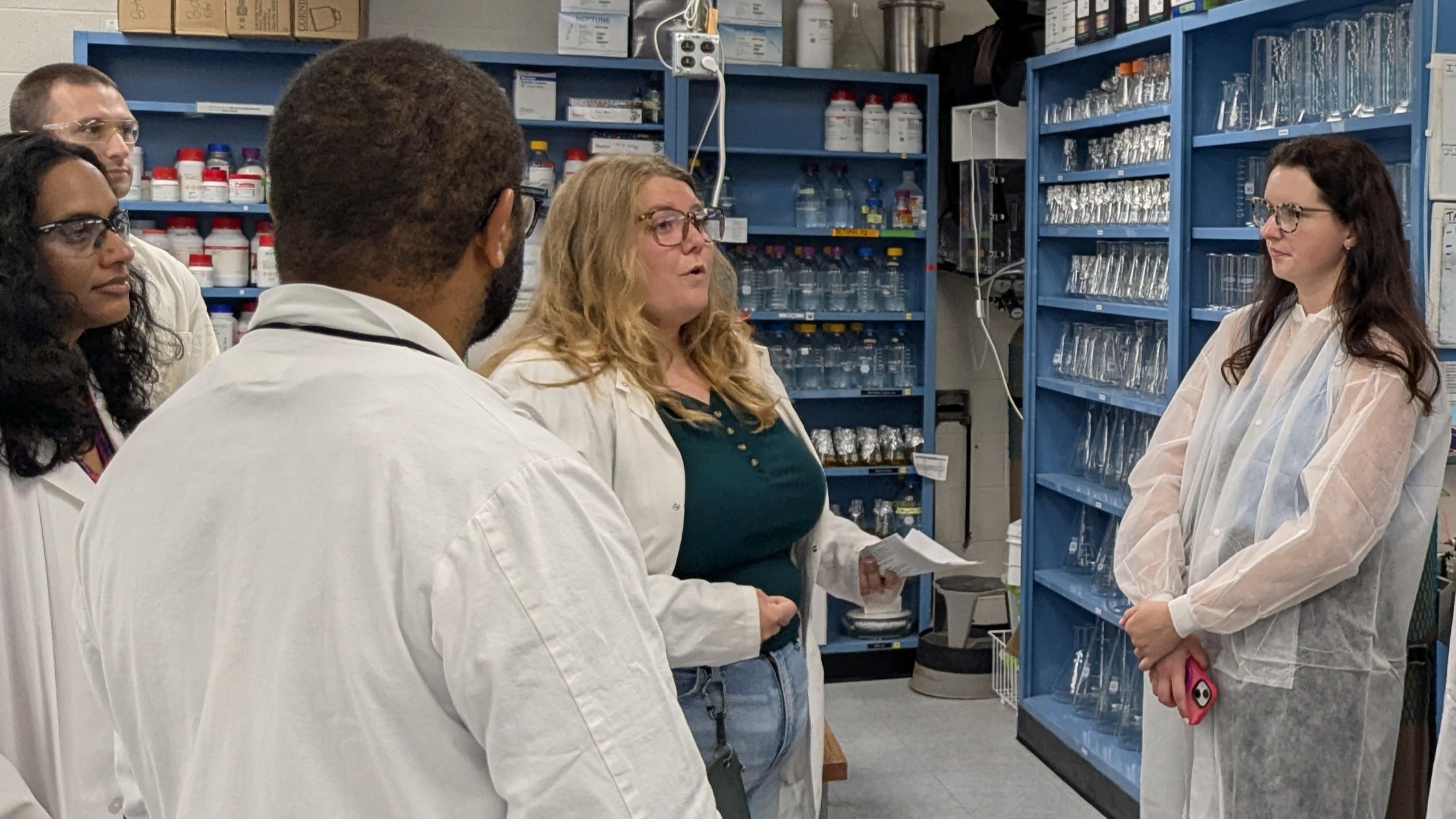 People in lab coats talk in a lab