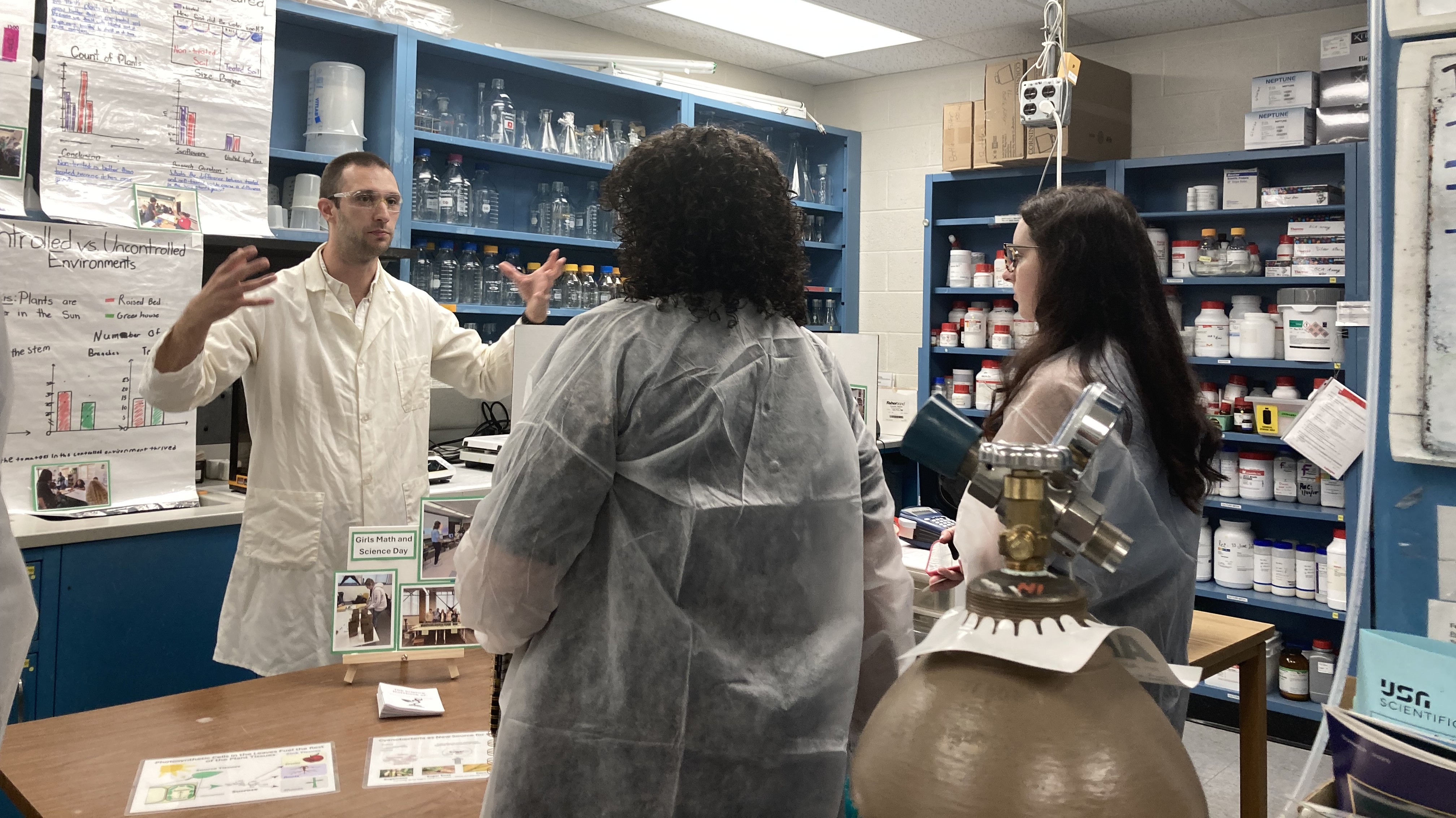 Three people in lab coats look at outreach materials